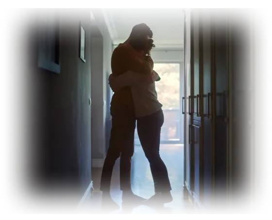 A couple holding each other close in the light of a doorway